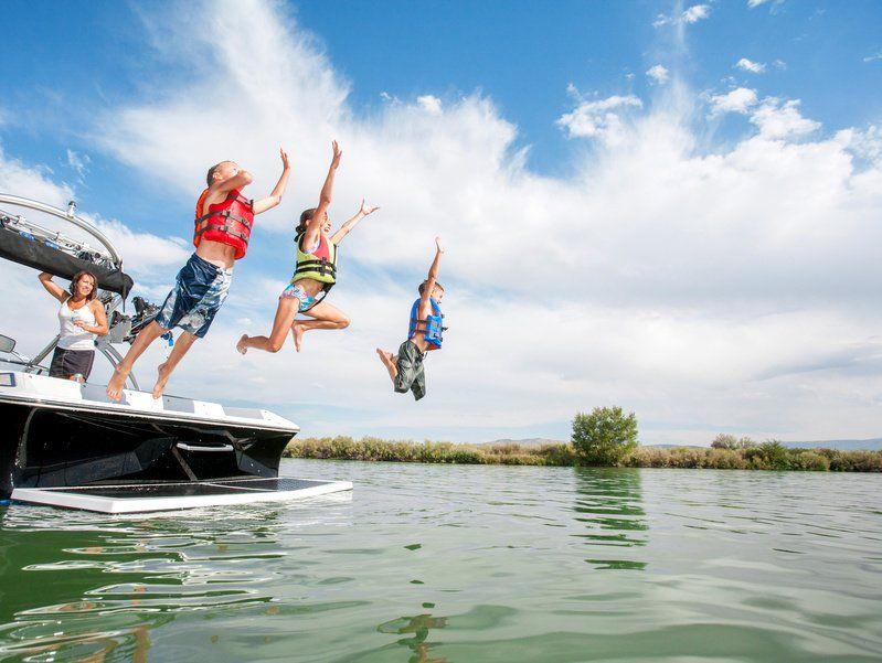 drei Kinder springen freudig vom Hausboot